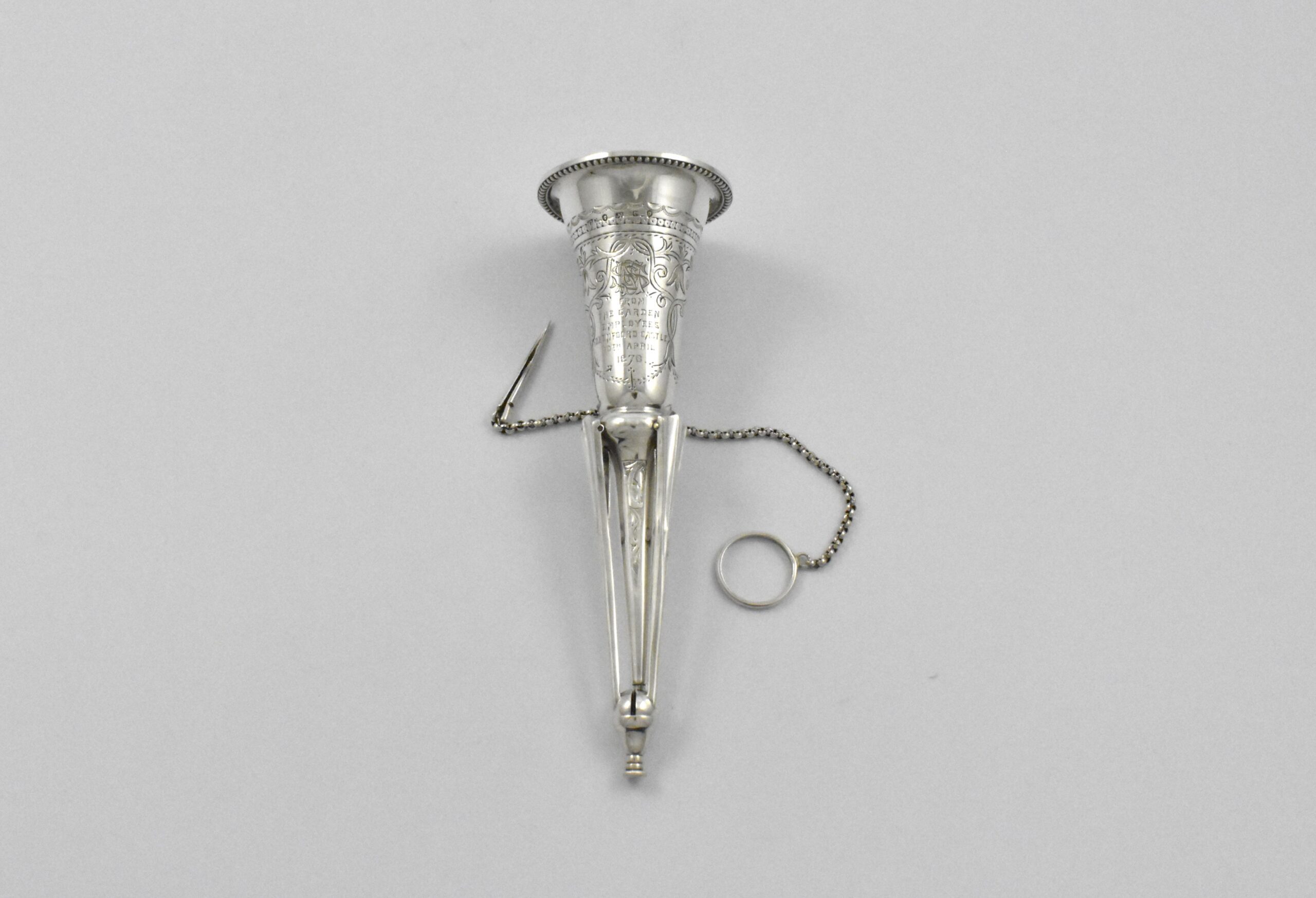 Victorian silver posy holder with finger ring and flower pin marked for London 1878. Incorporated into the handle are three sprung legs allowing it to stand. Engraved: “FROM THE GARDEN EMPLOYEES OXENFOORD CASTLE 10TH APRIL1878” by Colen Hewer Cheshire.