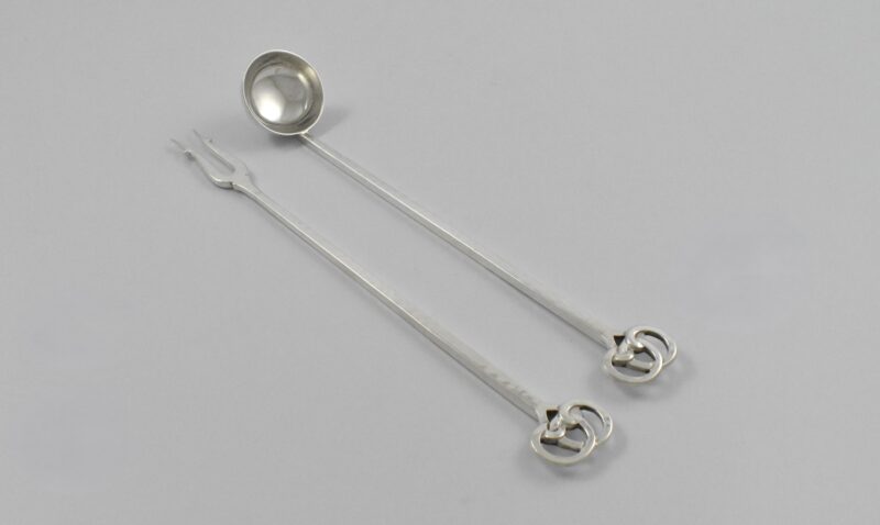 Art Deco silver cocktail set marked for Birmingham 1934, comprising a pickle fork and measuring spoon by George Laurence Connell. These have the optional Silver Jubilee mark.