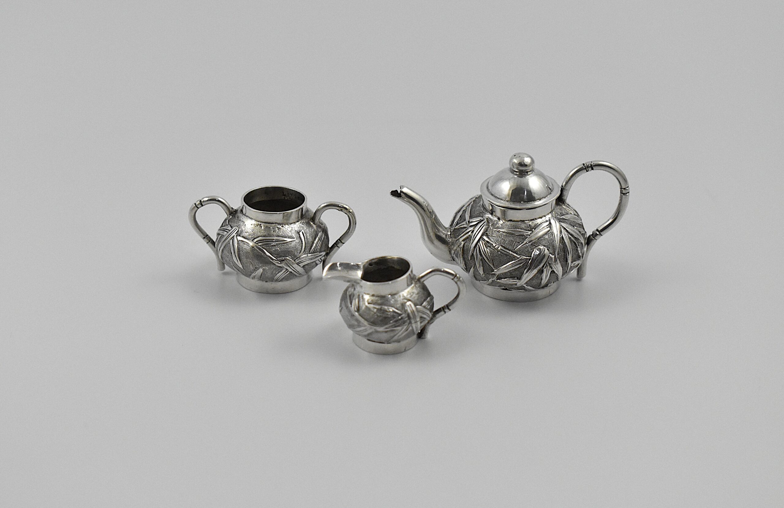 A late 19th century Chinese export silver miniature three piece tea set by Wang Hing, Canton & Shanghai, circa 1854-1925.