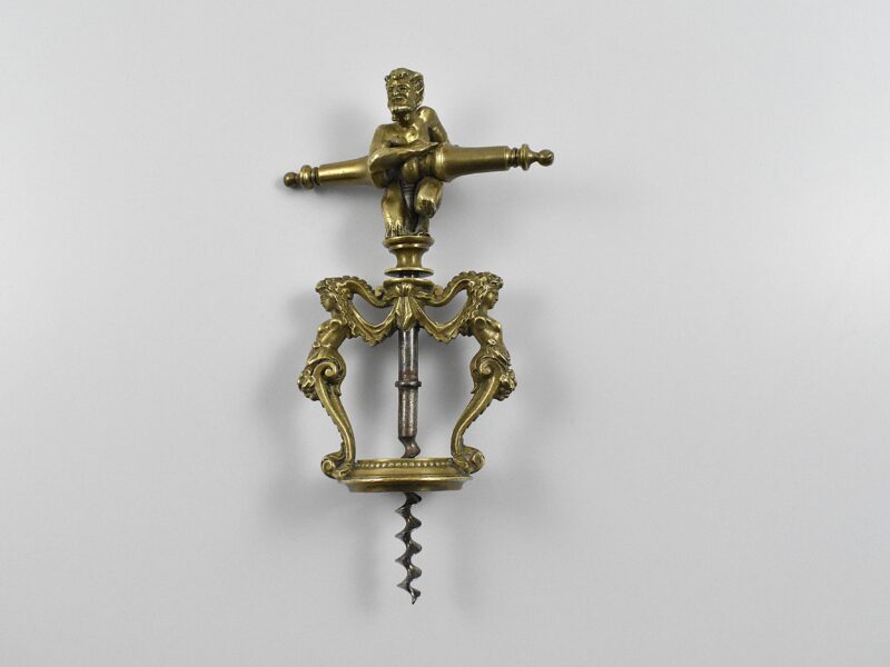 A magnificent two pillar cast brass corkscrew surmounted with a satyr embracing the handle. The two columns are caryatids and they stand on the bottle collar that allows centering of the perfect centre cut bladed worm. In Italian representations of a satyr as a man, he has a goat's ears, tail, legs and horns. This may suggest Italy as the source for this design. Circa 1860.