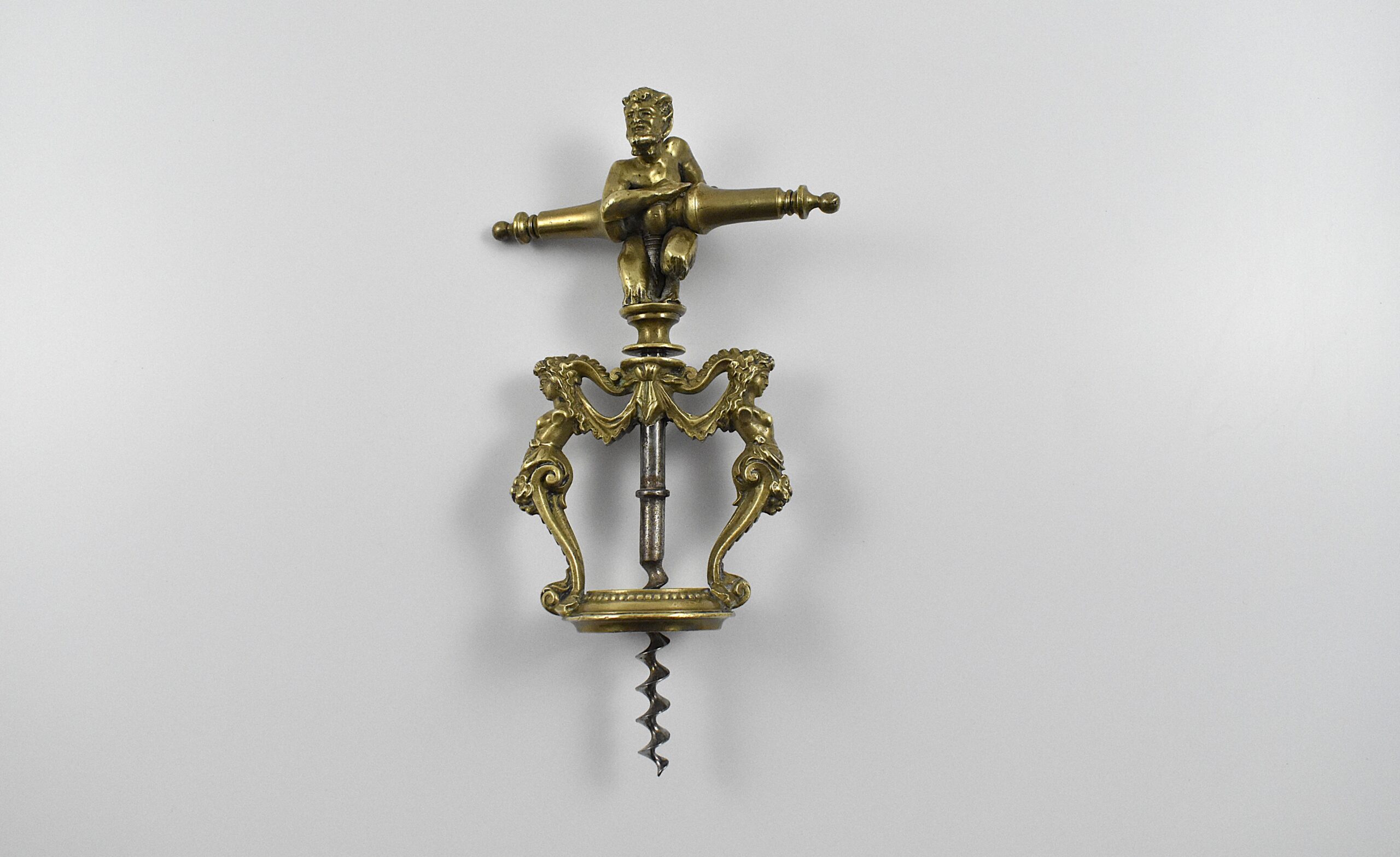 A magnificent two pillar cast brass corkscrew surmounted with a satyr embracing the handle. The two columns are caryatids and they stand on the bottle collar that allows centering of the perfect centre cut bladed worm. In Italian representations of a satyr as a man, he has a goat's ears, tail, legs and horns. This may suggest Italy as the source for this design. Circa 1860.