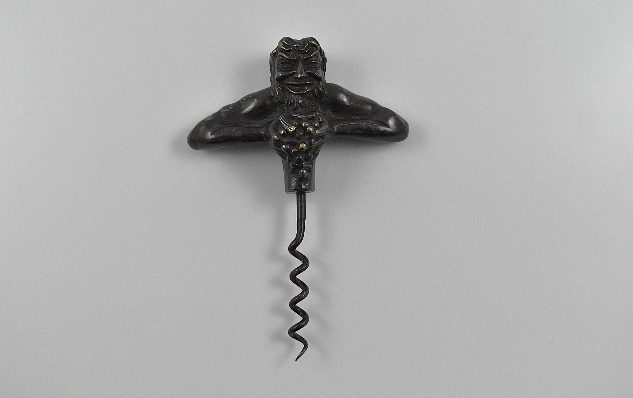 A bronze straight pull corkscrew with a representation of Bacchus squeezing a bunch of grapes.