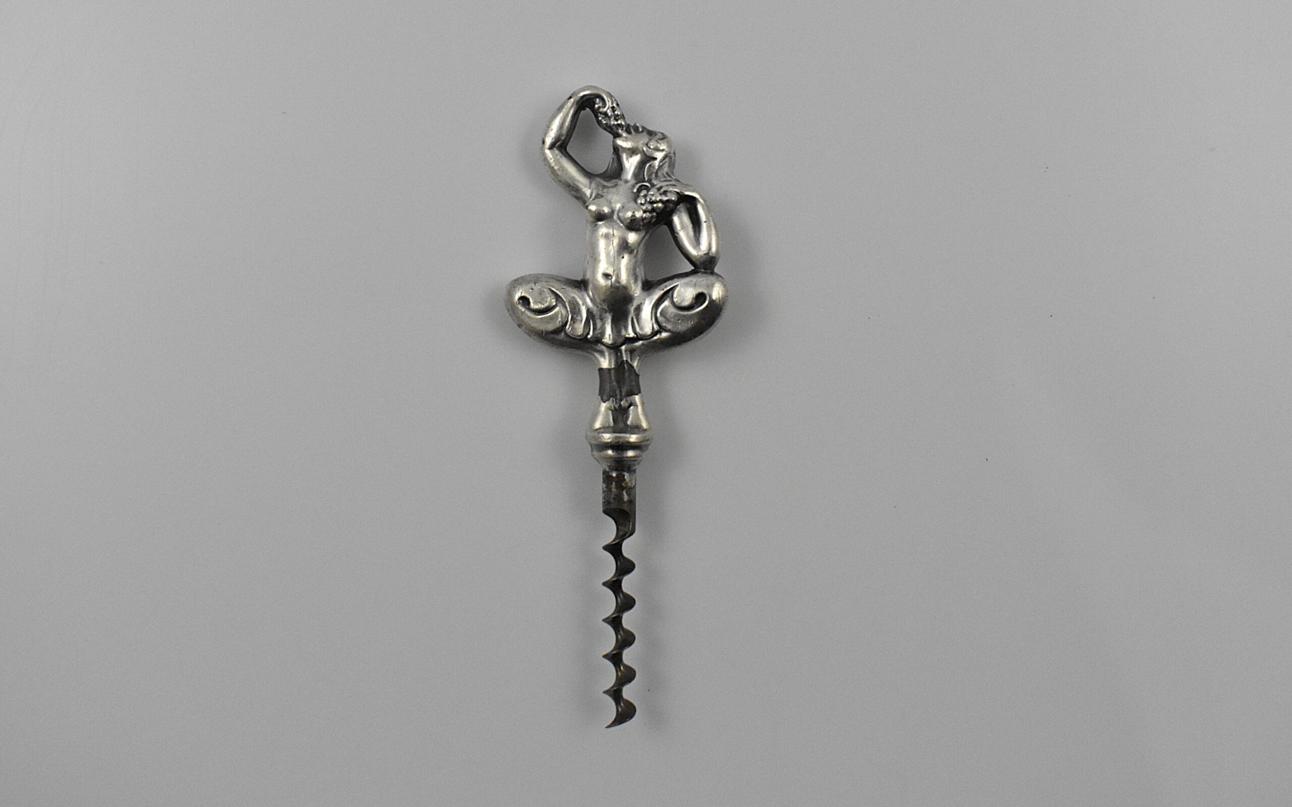 A Swedish straight pull corkscrew with a representation of a nude woman seductively eating grapes. This is marked “C.V.H” on the shank for the firm of Carl Victor Heljestrand (1816-1861).