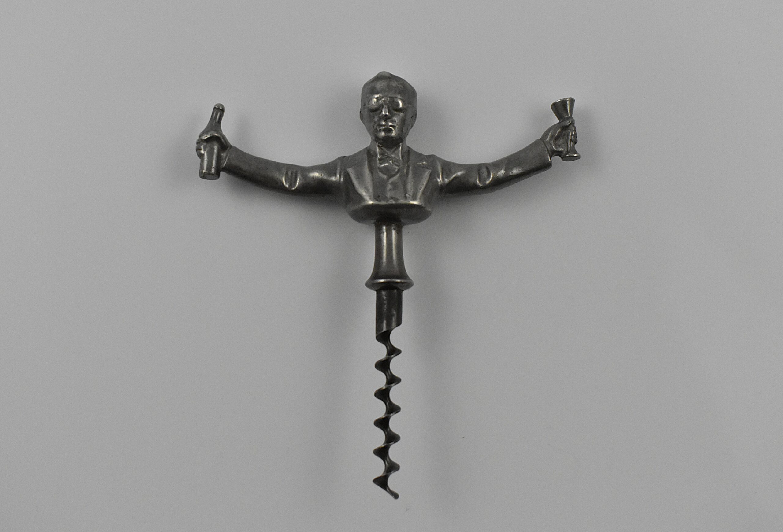 A Scandinavian straight pull cast pewter corkscrew with a representation of Ivan Bratt (1878- 1956) holding a bottle and glass in his outstretched arms. He was a Swedish politician who introduced the state – owned alcohol monopoly in 1917. He was detested for the introduction of the S. C. Bratt system which limited the purchase of no more than four litres of alcohol per month per person. This example marked “SWENSKIT TENN” (Swedish Pewter) under the back.