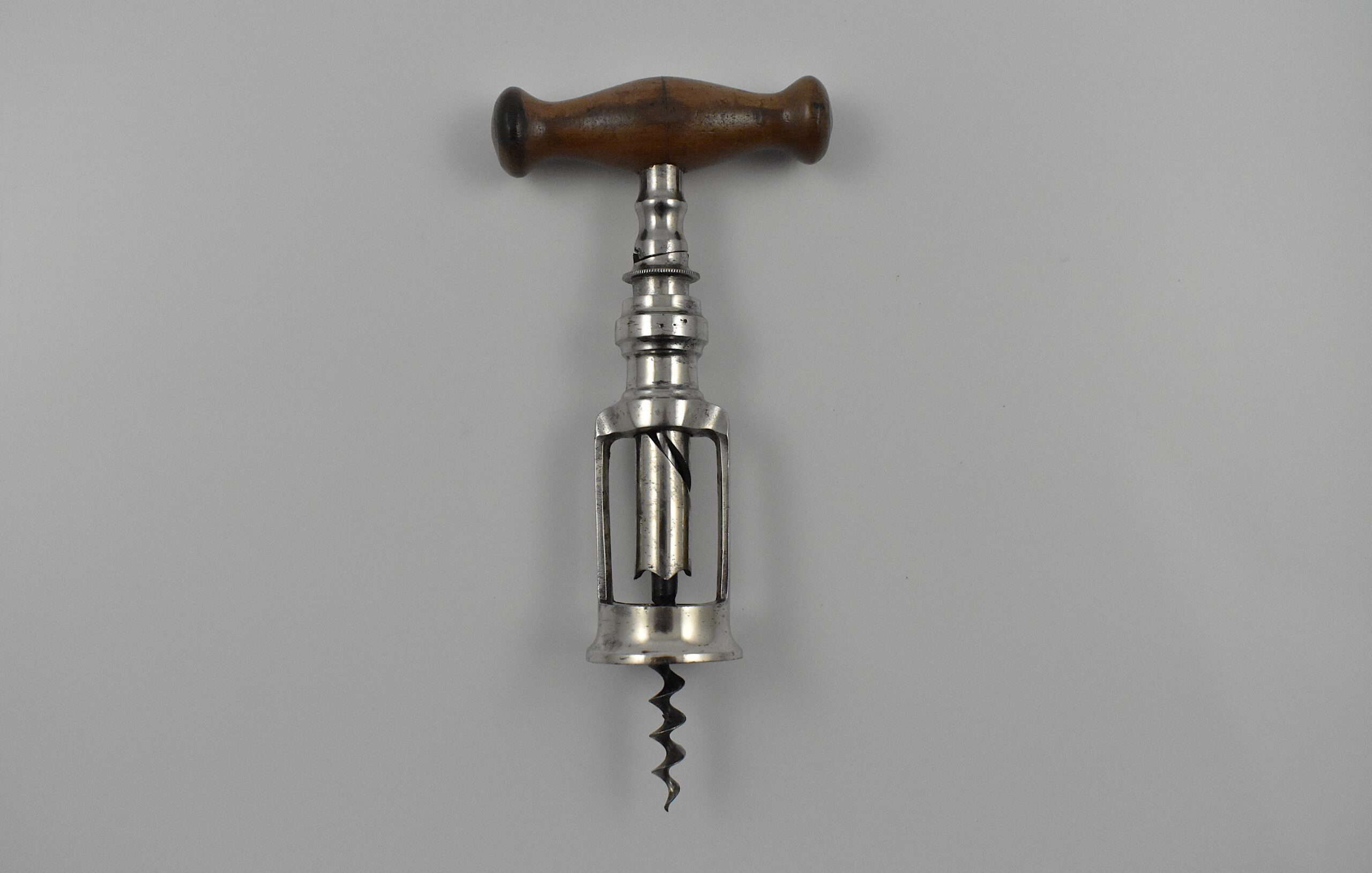 A German chrome plated steel open frame corkscrew with turned wood handle known as the “Mauser”. The handle is turned into the cork and when it engages the top of the second shaft this reverses and extracts the cork from the bottle. This was a German Empire registered design granted to Louis Kummer on the 14th of July 1904 and shown in his 1909 catalogue as the “Mauser”.