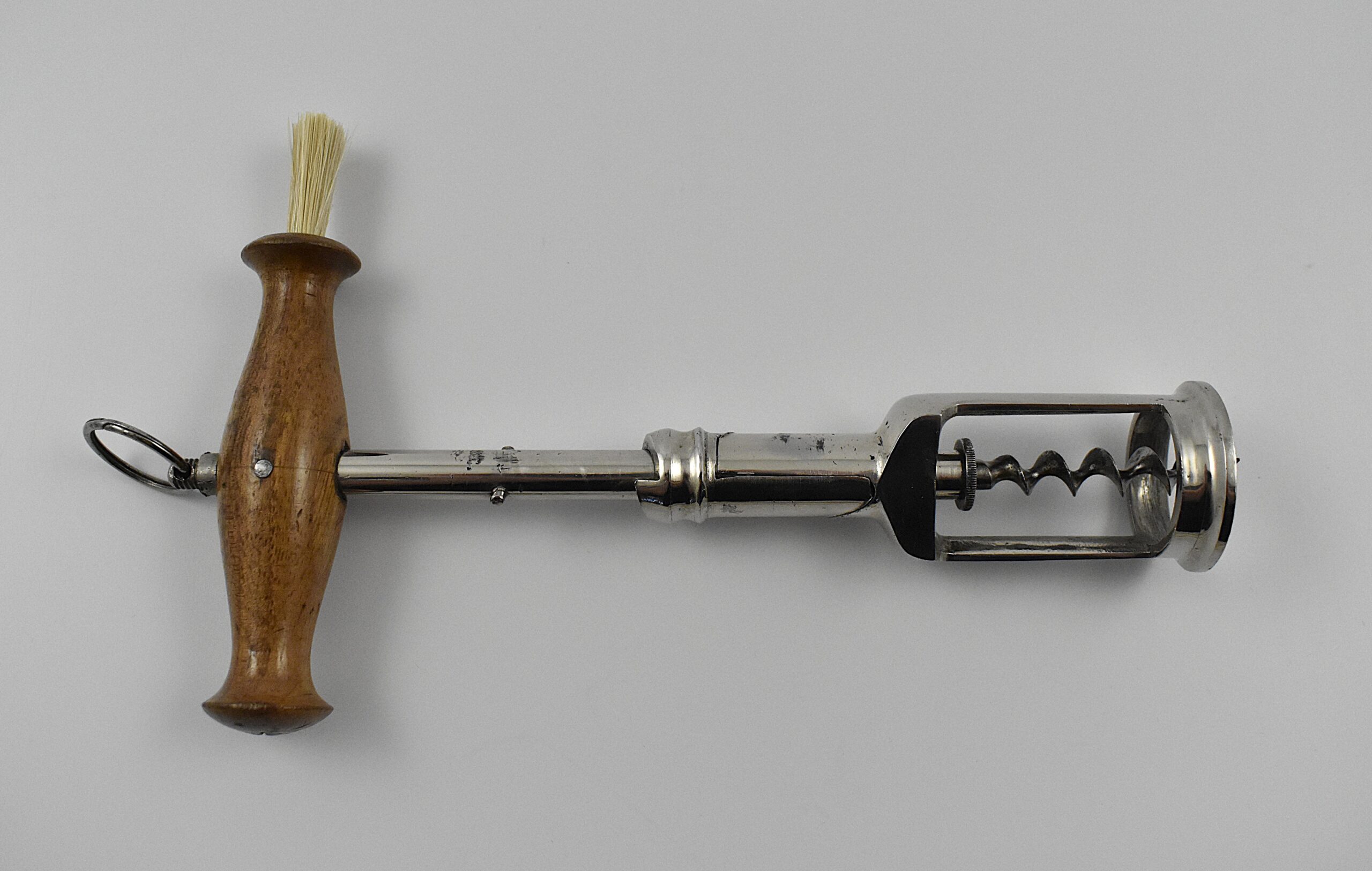 A German chrome plated steel open frame corkscrew with turned wood handle incorporating a dusting brush and hanging ring. The handle is turned into the cork and when the two pins in the shaft engage the top of the second shaft, this reverses and extracts the cork from the bottle. This design originates from the 1880 German patent taken out by Freidrich Kummer and later adapted by his son Louis Kummer. Perfect centre cut bladed worm. - Image 2