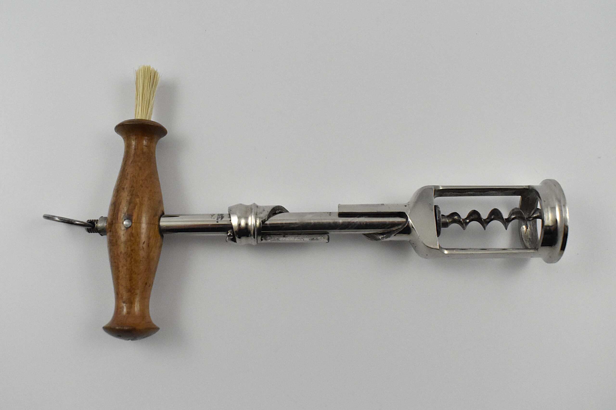 A German chrome plated steel open frame corkscrew with turned wood handle incorporating a dusting brush and hanging ring. The handle is turned into the cork and when the two pins in the shaft engage the top of the second shaft, this reverses and extracts the cork from the bottle. This design originates from the 1880 German patent taken out by Freidrich Kummer and later adapted by his son Louis Kummer. Perfect centre cut bladed worm. - Image 3