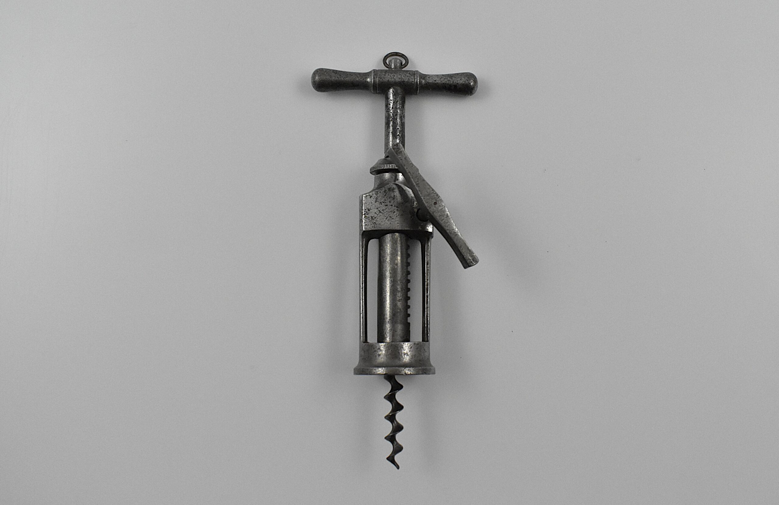A German steel open frame corkscrew with side rack. The handle with a hanging ring leads to a threaded shank, and the second shaft has a machined side rack. Once the cork is penetrated the flat steel side wind raising handle pulls the cork from the bottle. This design has a cork ejector, the claws on the base of the second shaft, which helps eject the drawn cork from the perfect centre cut bladed worm by turning the handle in the opposite direction, without having to hold the cork. This example is marked “F OTTO MULLER” on the frame.
