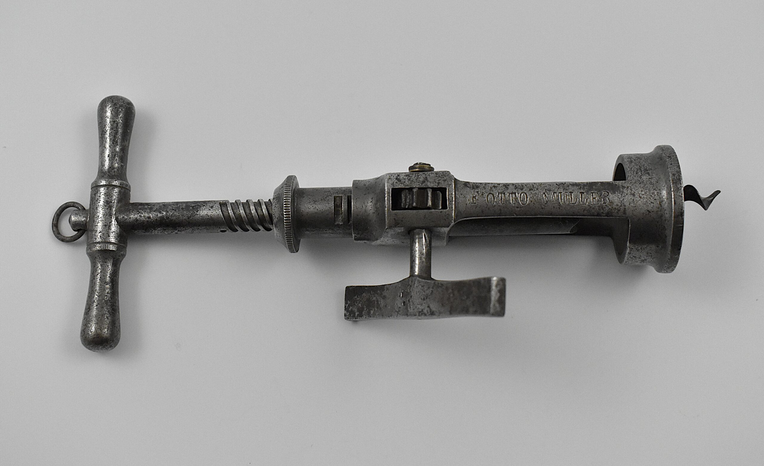 A German steel open frame corkscrew with side rack. The handle with a hanging ring leads to a threaded shank, and the second shaft has a machined side rack. Once the cork is penetrated the flat steel side wind raising handle pulls the cork from the bottle. This design has a cork ejector, the claws on the base of the second shaft, which helps eject the drawn cork from the perfect centre cut bladed worm by turning the handle in the opposite direction, without having to hold the cork. This example is marked “F OTTO MULLER” on the frame. - Image 4