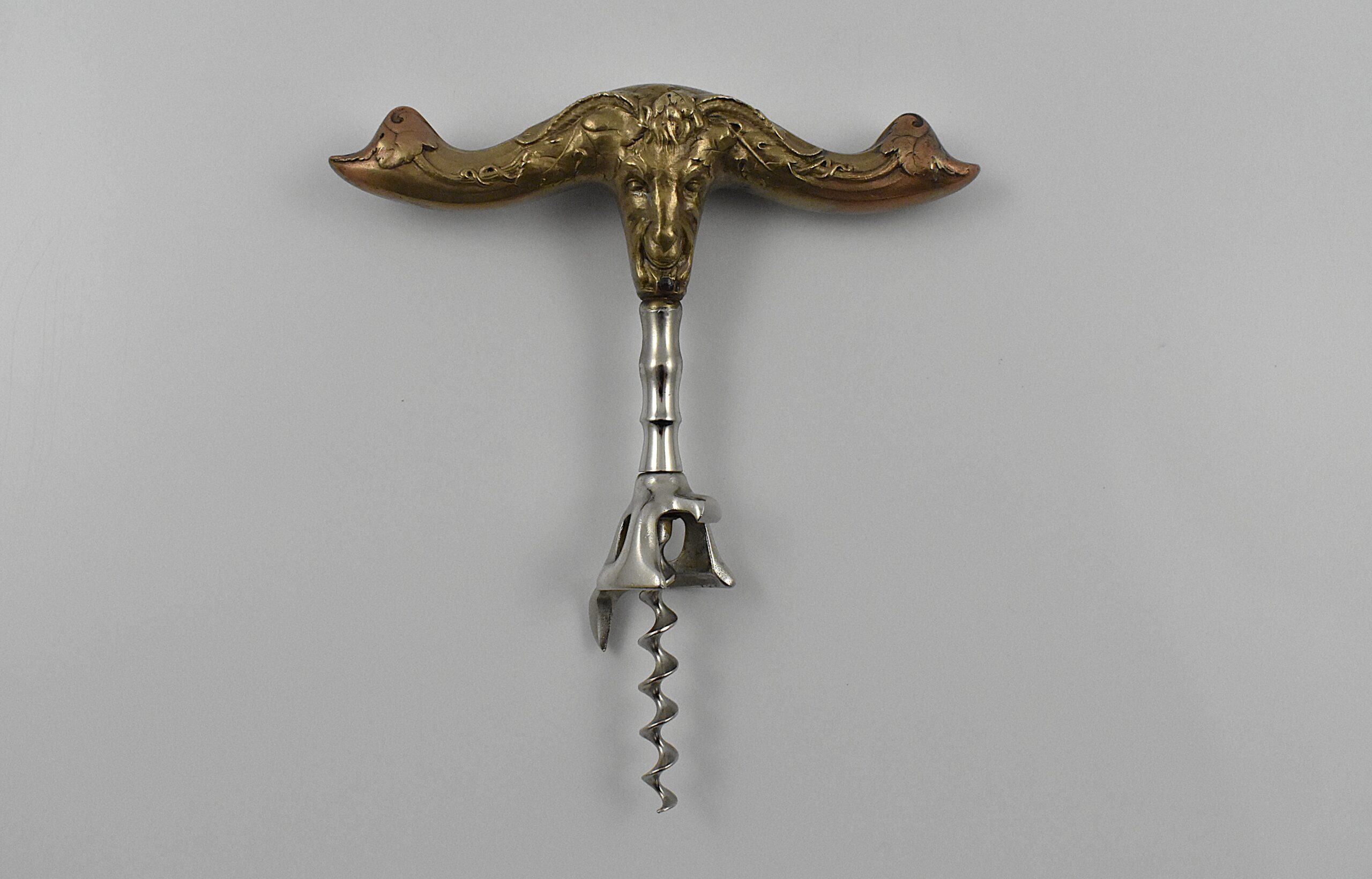 An American hollow brass handled bell cap corkscrew by Reed & Barton with internal rolling ball, the bell cap designed by Walker. The handle moulded with a figure of Baccus and grape vines and is marked “REED & BARTON’ on one side and “42 BN” on the other.