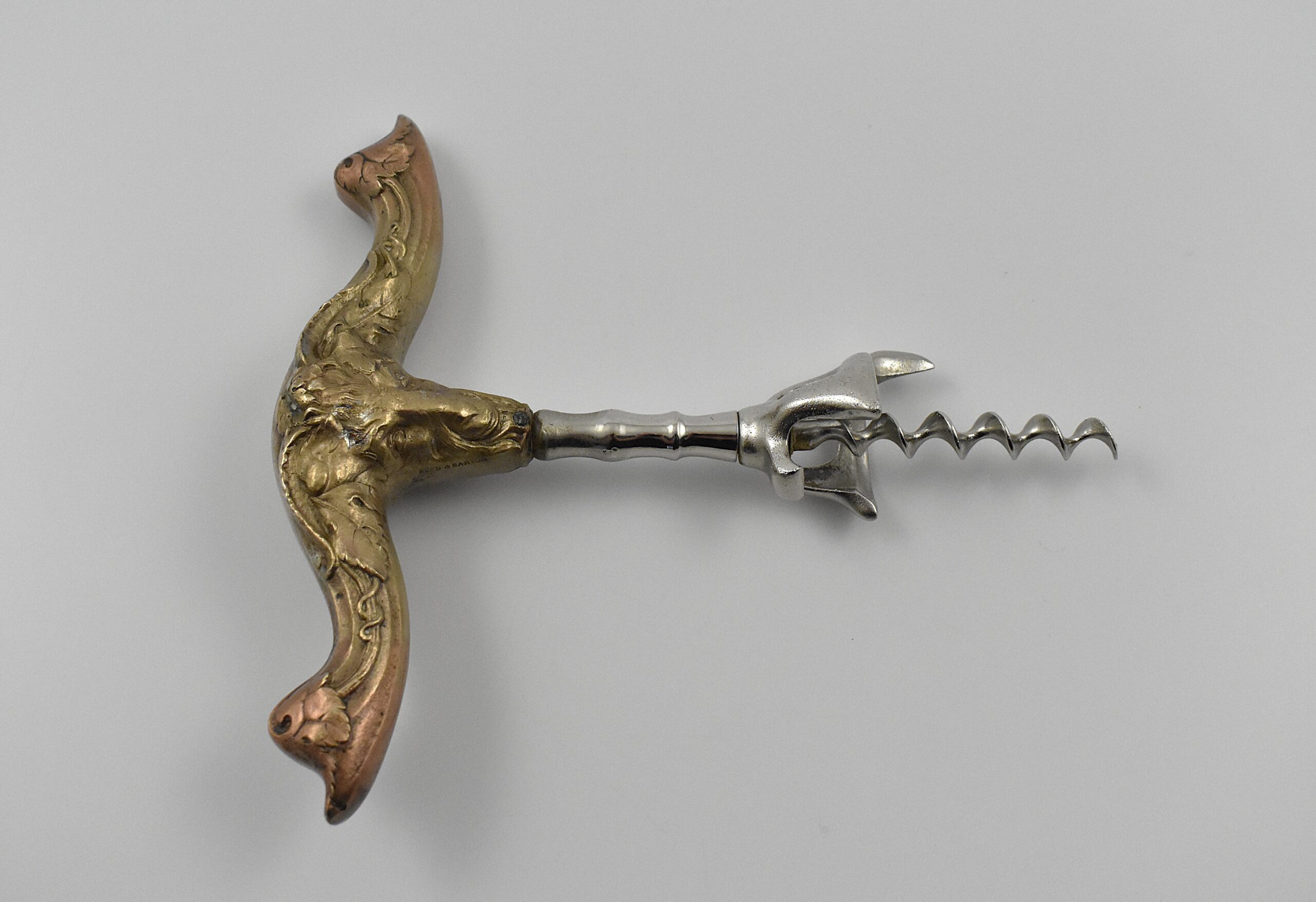 An American hollow brass handled bell cap corkscrew by Reed & Barton with internal rolling ball, the bell cap designed by Walker. The handle moulded with a figure of Baccus and grape vines and is marked “REED & BARTON’ on one side and “42 BN” on the other. - Image 2